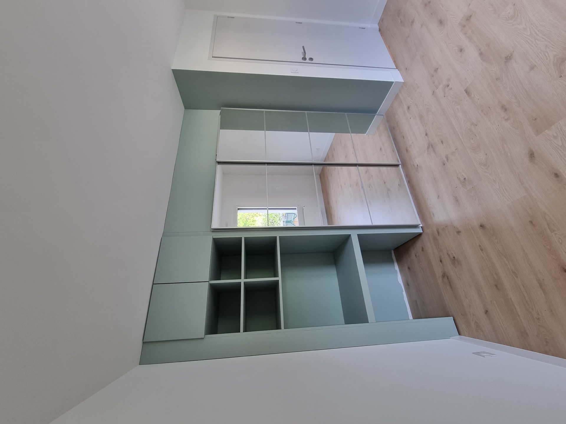 Chambre à Biarritz : agencement sur-mesure peint en vert sauge avec placards à portes coulissantes miroir