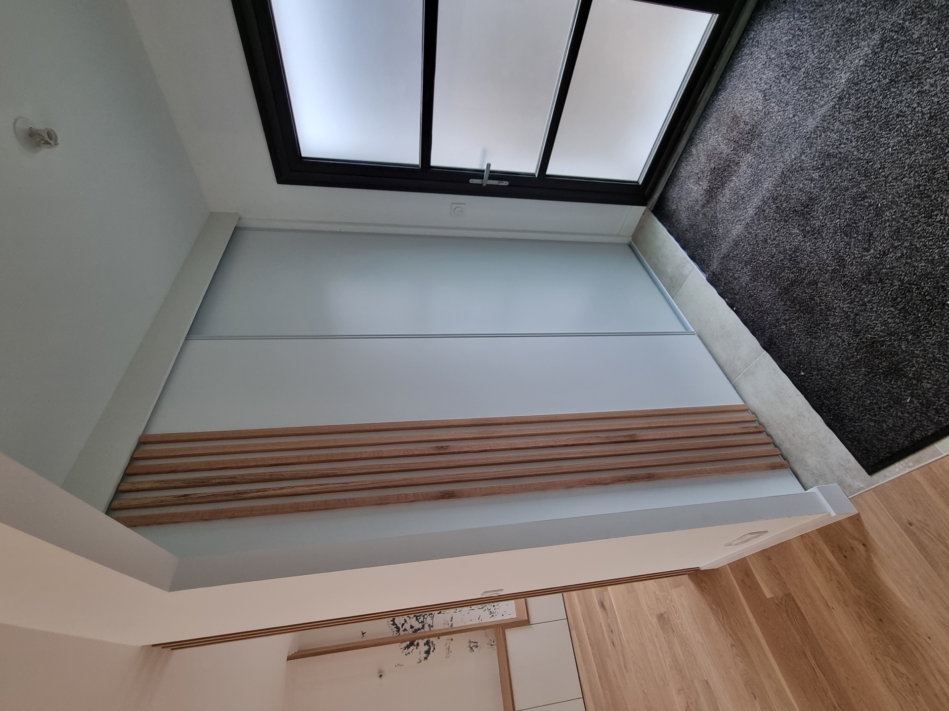 Entrée d'une maison à Biarritz : placard à portes coulissantes habillé de tasseaux chêne verticaux