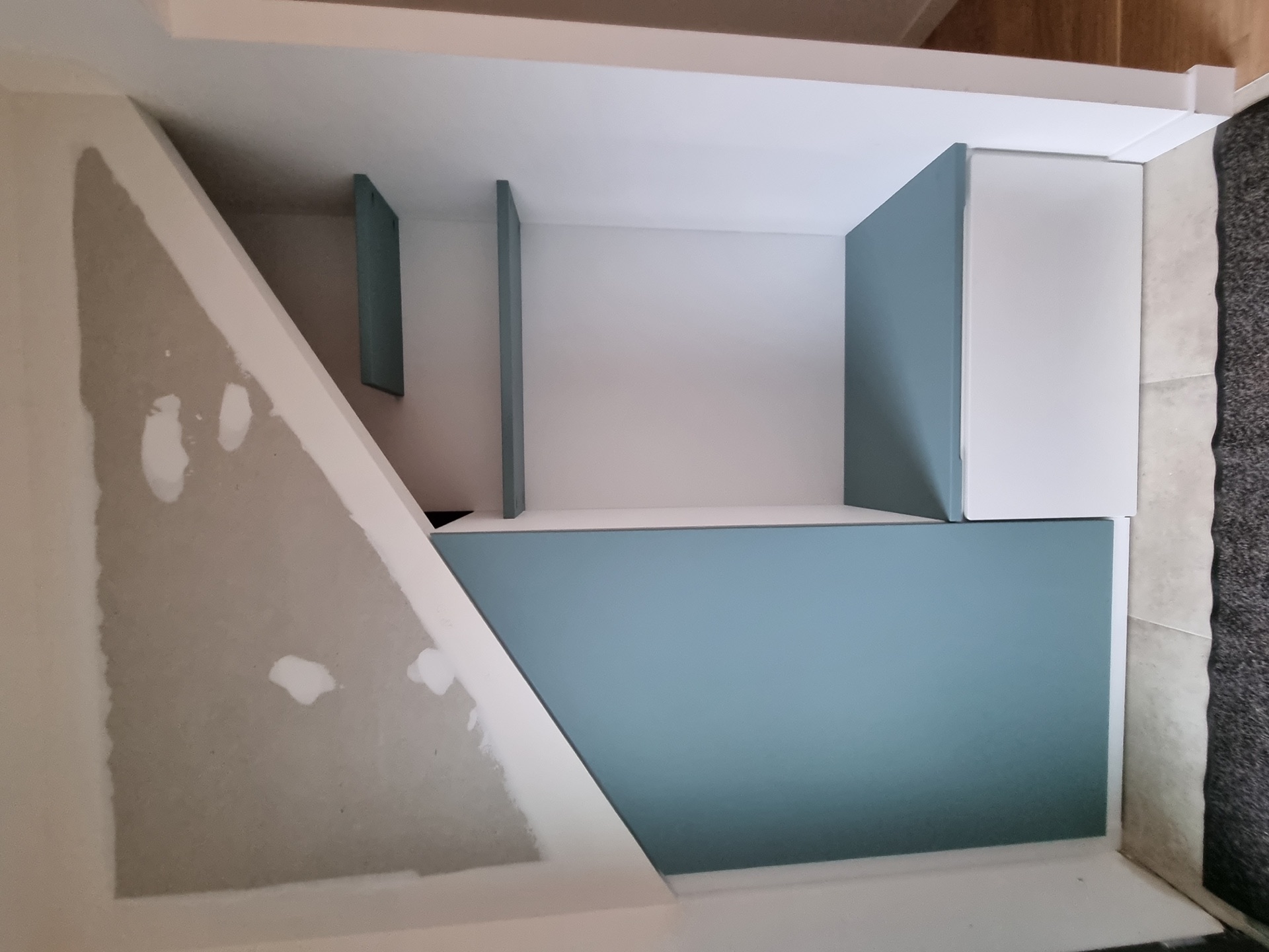 Rangement sous escalier sur-mesure peint en bleu canard dans une maison à Biarritz