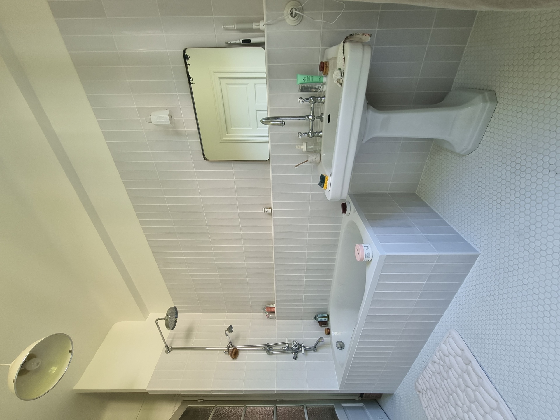 Salle de bain rénovée à Biarritz centre avec carrelage métro vertical blanc, baignoire habillée, vasque colonne et sol mosaïque hexagonale
