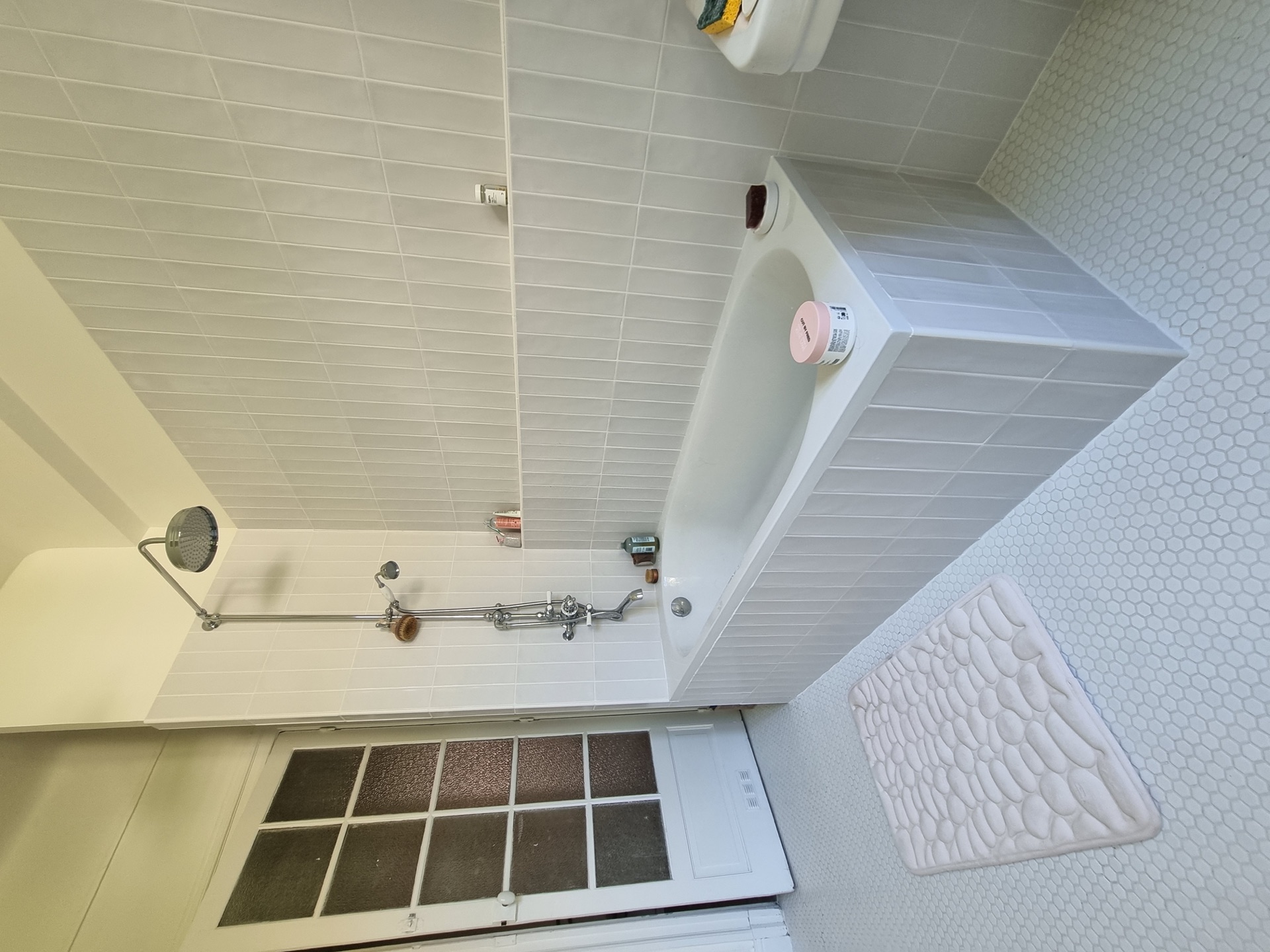 Baignoire habillée du carrelage métro vertical et robinetterie chromée à croisillons dans une salle de bain rétro à Biarritz