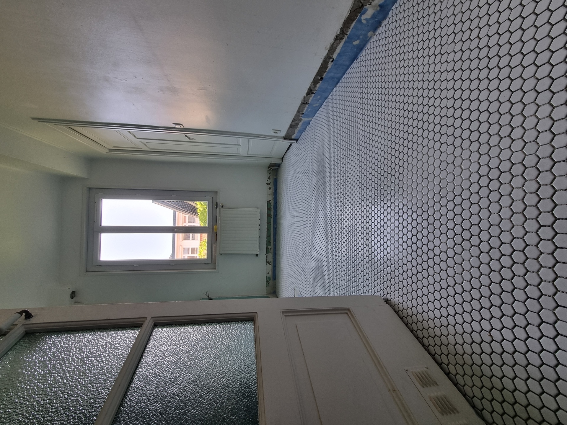 Sol en mosaïque hexagonale blanche à joints époxy dans une salle de bain rénovée à Biarritz